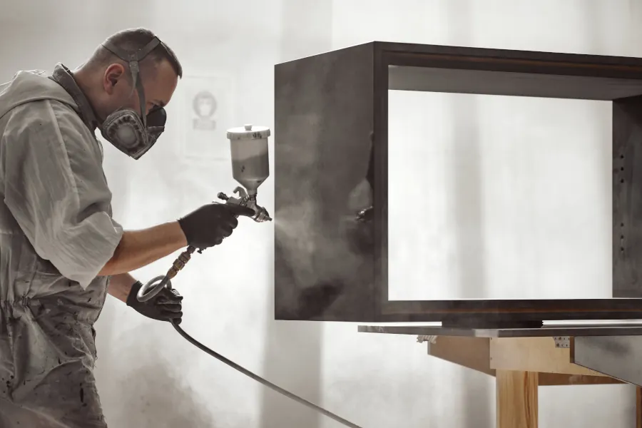 Man Spraying Piece Of Furniture